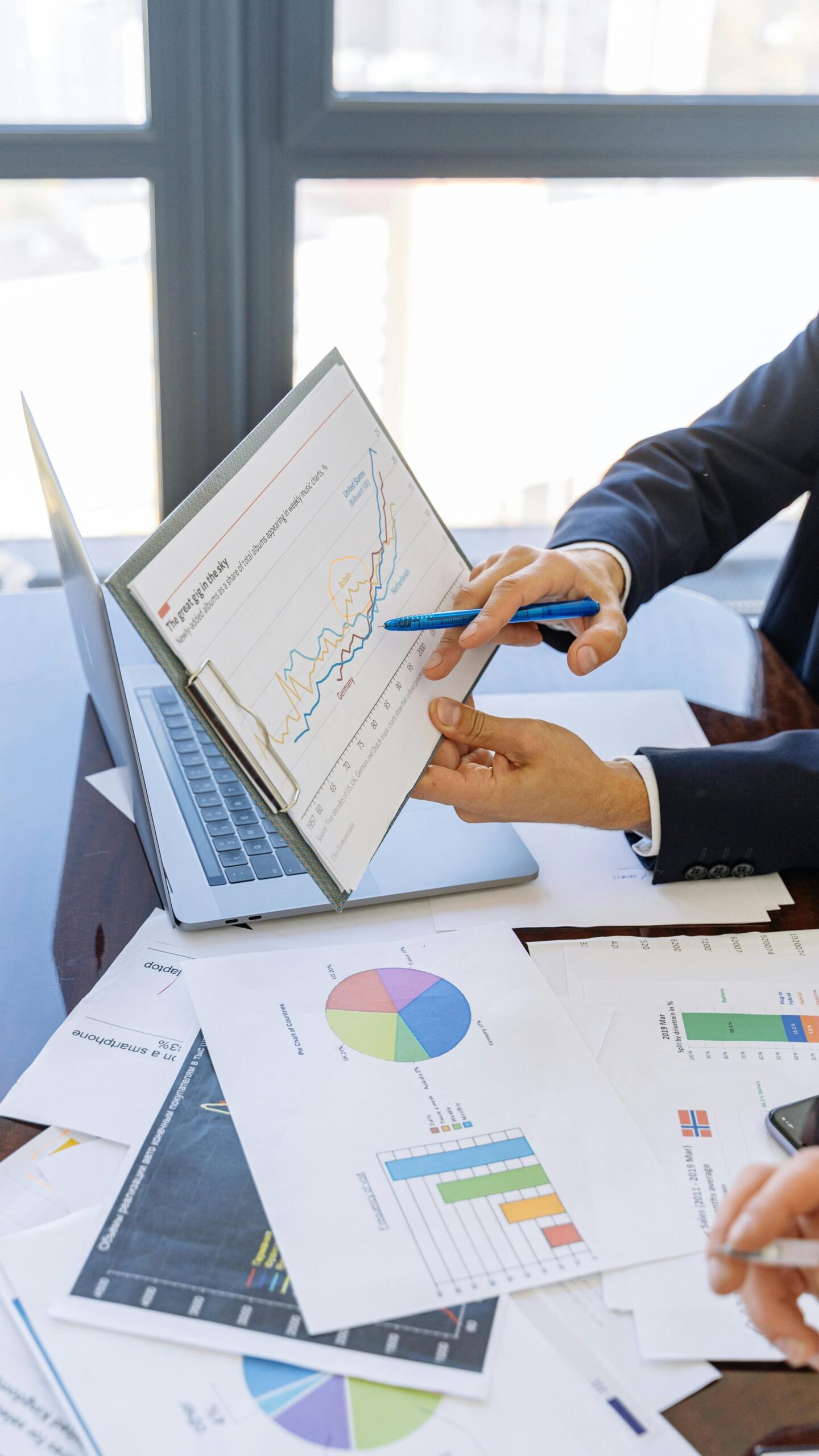 Accueil Business professionals discussing financial graphs and charts in an office setting.
